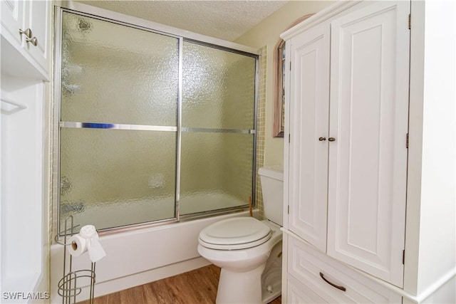 bathroom with toilet, shower / bath combination with glass door, hardwood / wood-style floors, and a textured ceiling