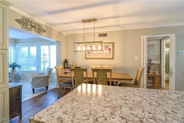 dining space featuring ornamental molding and dark wood-type flooring