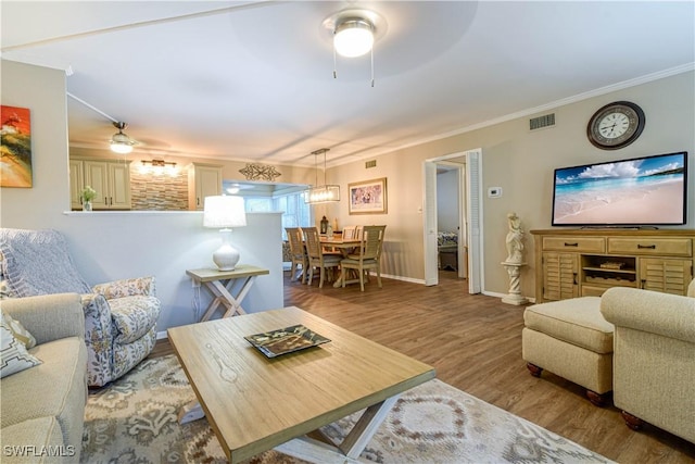 living room featuring crown molding, ceiling fan, and light wood-type flooring