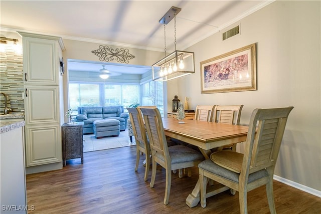 dining space featuring sink, crown molding, and dark hardwood / wood-style floors