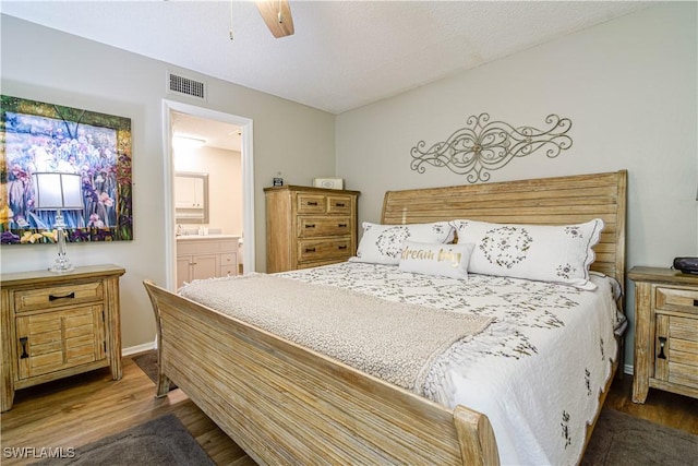 bedroom featuring dark hardwood / wood-style flooring, ensuite bath, a textured ceiling, and ceiling fan