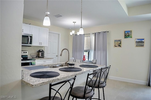 320 Ranch Ave, Lehigh Acres, FL 33974 - kitchen with stainless steel appliances, a sink, white cabinets, and a kitchen breakfast bar