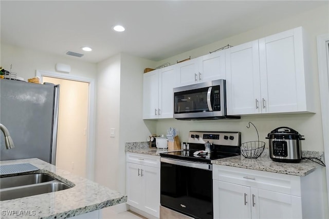 320 Ranch Ave, Lehigh Acres, FL 33974 - kitchen featuring appliances with stainless steel finishes, a sink, white cabinets, light stone countertops, and recessed lighting
