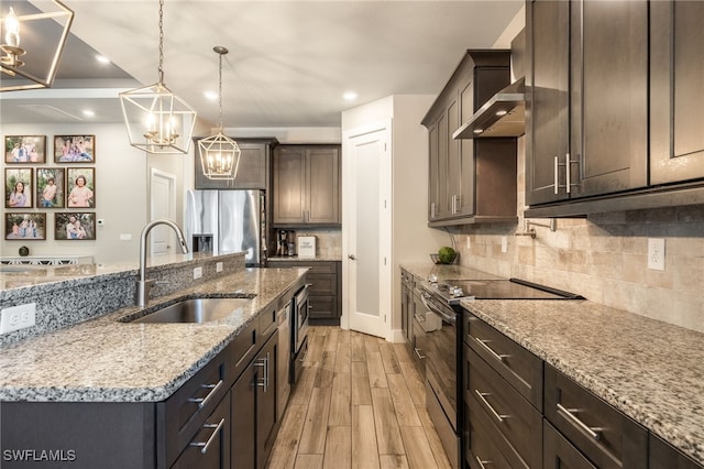 kitchen with stainless steel fridge with ice dispenser, a kitchen island with sink, light stone countertops, and electric range