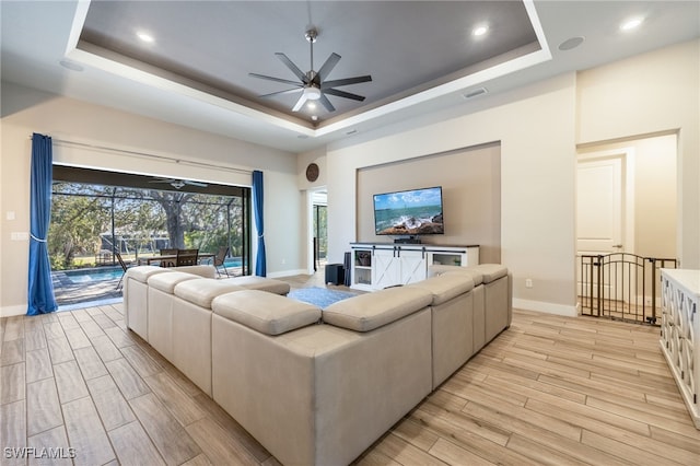 living room featuring a tray ceiling, ceiling fan, and a towering ceiling