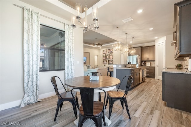 dining area with ceiling fan with notable chandelier and light hardwood / wood-style floors