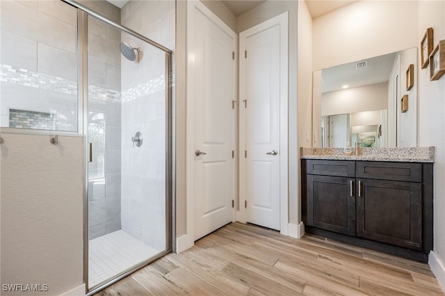 bathroom with vanity, hardwood / wood-style floors, and a shower with door