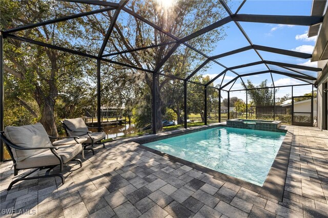 view of swimming pool featuring an in ground hot tub, a patio, a water view, and glass enclosure