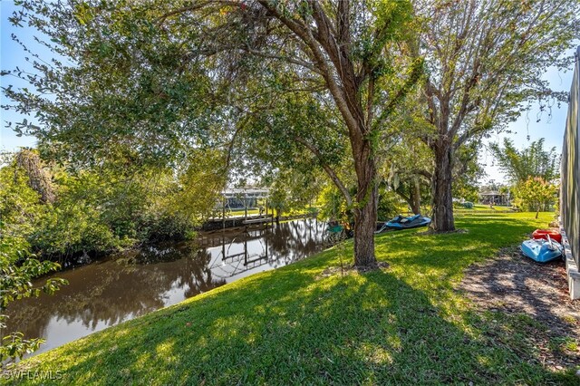 view of dock with a yard and a water view