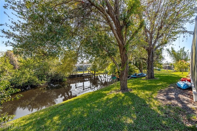 view of dock with a yard and a water view