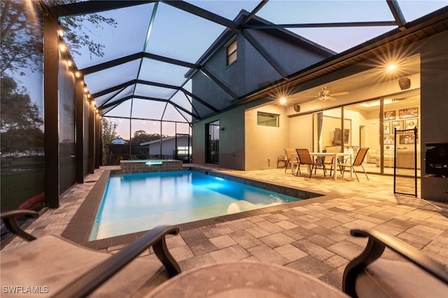 pool at dusk featuring a patio area, an in ground hot tub, ceiling fan, and glass enclosure