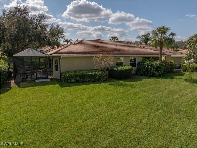 rear view of property featuring a yard and glass enclosure