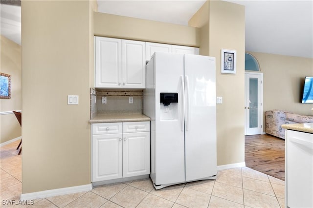 kitchen with backsplash, white refrigerator with ice dispenser, white cabinets, and light tile patterned flooring