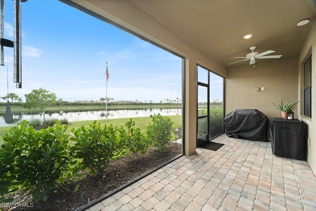unfurnished sunroom with a water view and ceiling fan