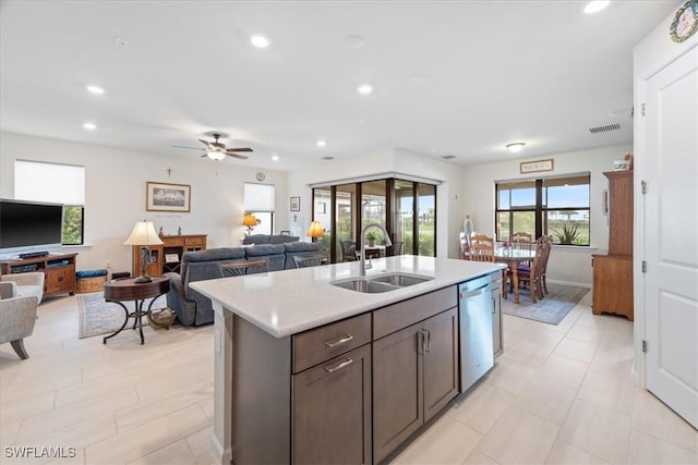 kitchen with sink, ceiling fan, dark brown cabinets, a center island with sink, and stainless steel dishwasher