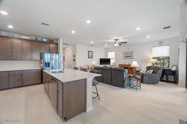 kitchen featuring dark brown cabinetry, a breakfast bar area, sink, and a center island with sink