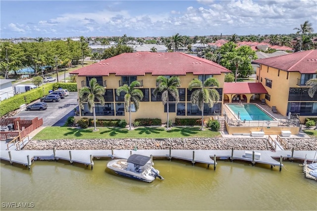 1400 Blue Point Ave Unit 207, Naples, FL 34102 - rear view of property with a community pool, stucco siding, a tiled roof, and a water view