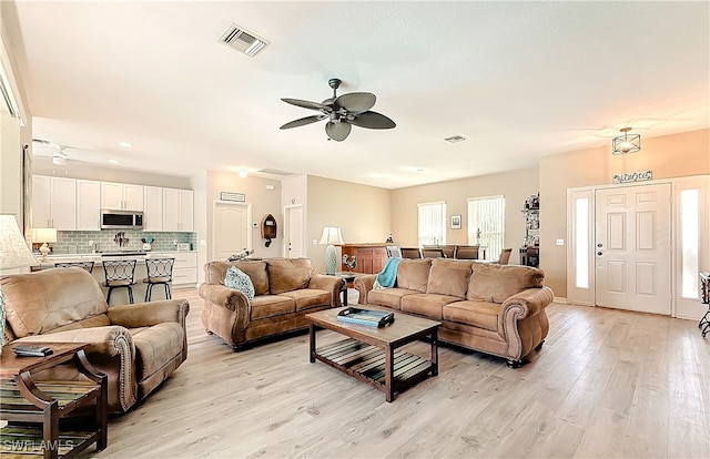 living room with ceiling fan and light hardwood / wood-style flooring