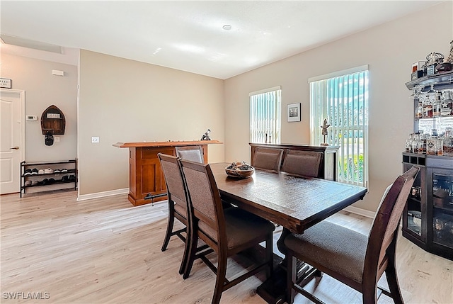 dining area featuring indoor bar and light wood-type flooring