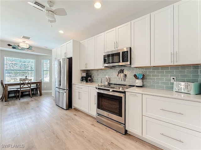 kitchen with white cabinetry, appliances with stainless steel finishes, light hardwood / wood-style floors, and backsplash