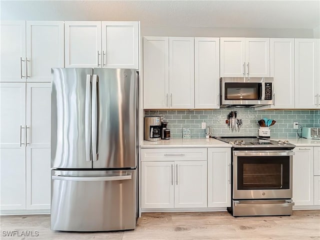 kitchen featuring stainless steel appliances, white cabinetry, tasteful backsplash, and light hardwood / wood-style floors