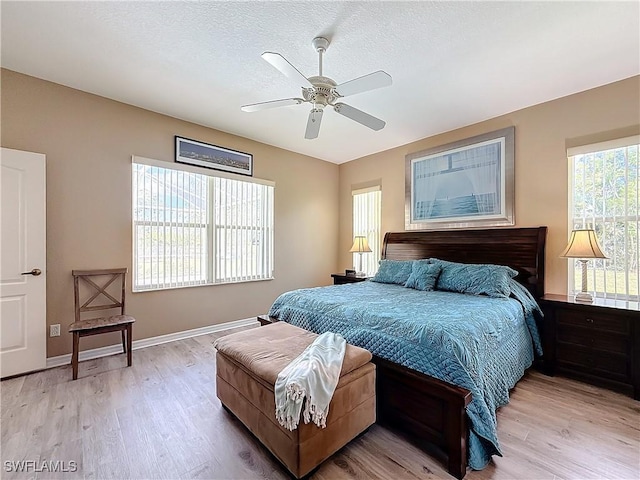 bedroom with ceiling fan, light hardwood / wood-style floors, and a textured ceiling