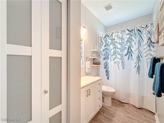 bathroom with hardwood / wood-style flooring, vanity, toilet, and walk in shower