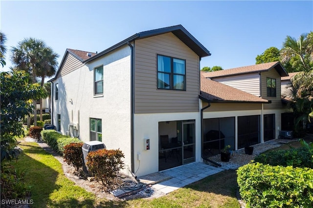 back of property featuring a lawn and a sunroom