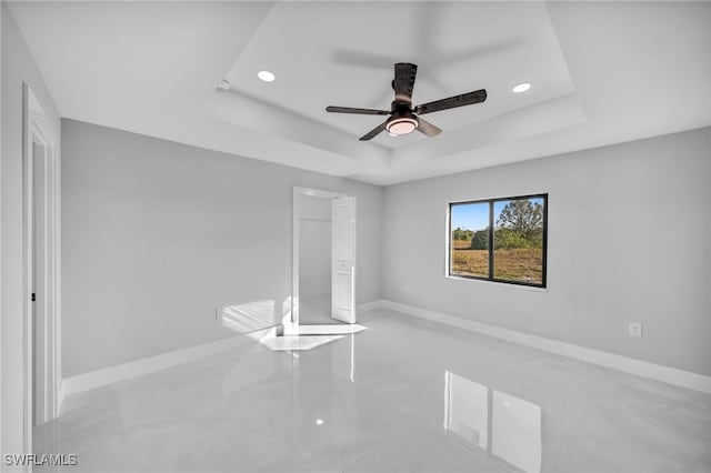 unfurnished bedroom with ceiling fan, a tray ceiling, and a closet