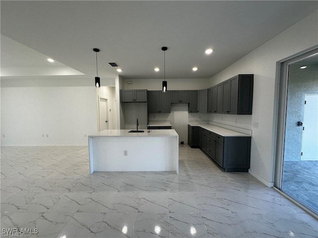 kitchen with a kitchen island with sink, hanging light fixtures, gray cabinets, and sink