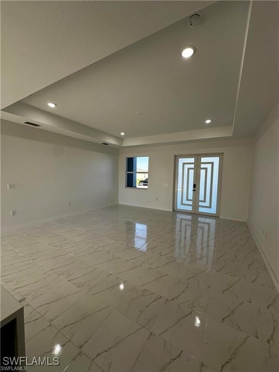 unfurnished living room featuring a raised ceiling and french doors