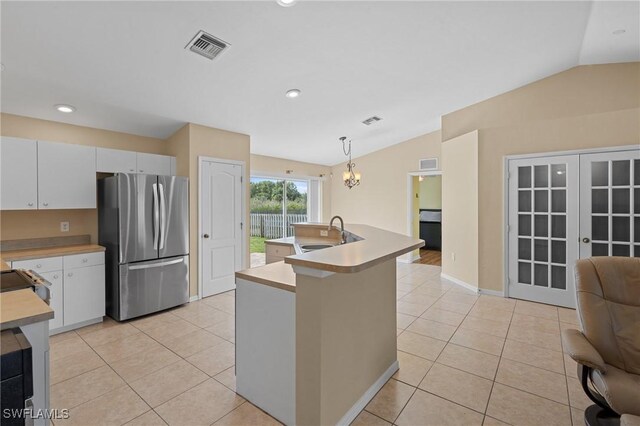 kitchen with lofted ceiling, light tile patterned floors, a sink, and freestanding refrigerator