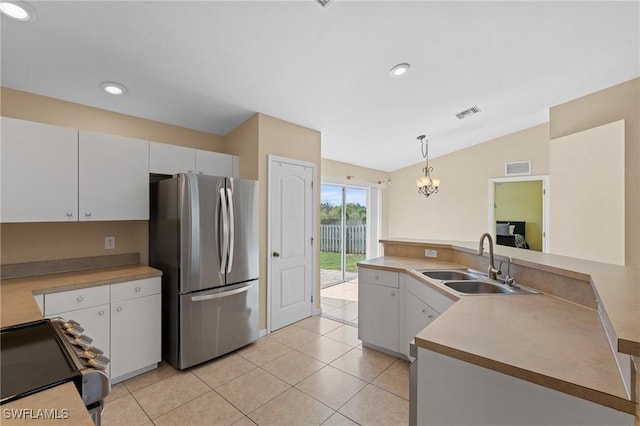 kitchen featuring a sink, vaulted ceiling, electric stove, hanging light fixtures, and freestanding refrigerator