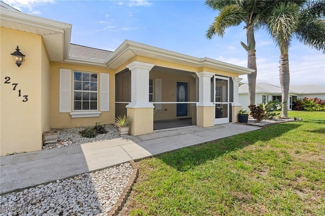 entrance to property featuring a yard and stucco siding