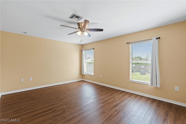 spare room with a ceiling fan, baseboards, visible vents, and dark wood-style flooring