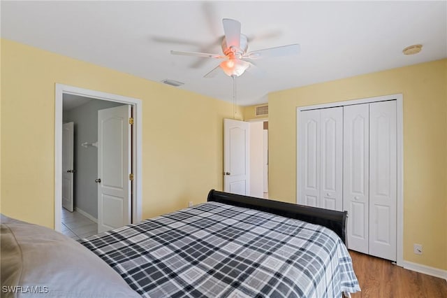 bedroom featuring baseboards, visible vents, ceiling fan, wood finished floors, and a closet