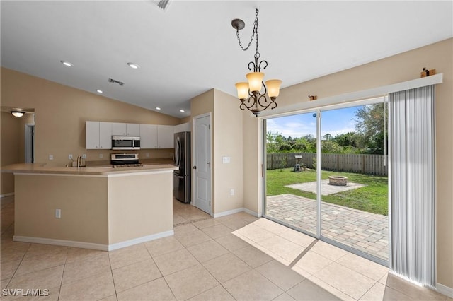 kitchen with stainless steel appliances, lofted ceiling, light countertops, light tile patterned flooring, and a sink