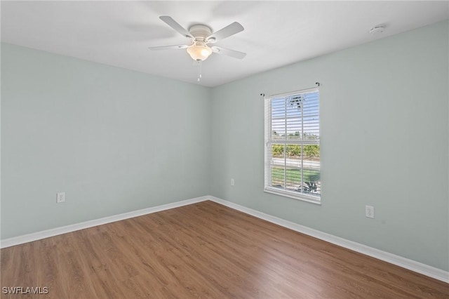 unfurnished room with ceiling fan, wood finished floors, and baseboards