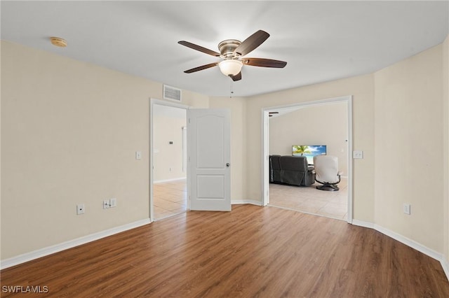 empty room featuring visible vents, ceiling fan, baseboards, and wood finished floors