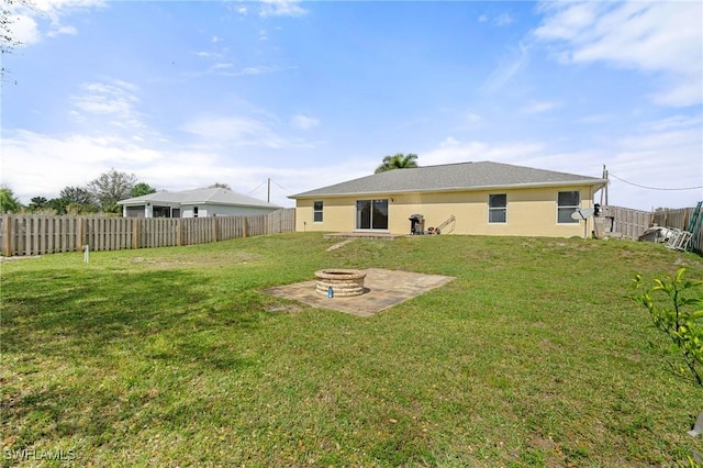 rear view of house featuring a fire pit, a yard, and a fenced backyard