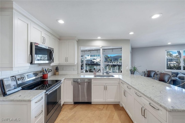 kitchen with white cabinetry, sink, kitchen peninsula, stainless steel appliances, and light hardwood / wood-style flooring