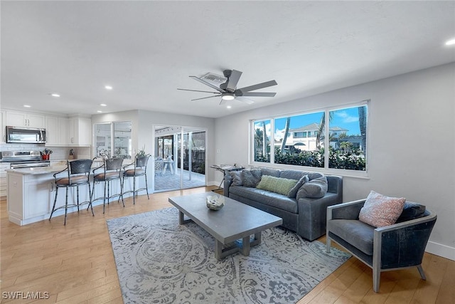 living room with light hardwood / wood-style floors and ceiling fan