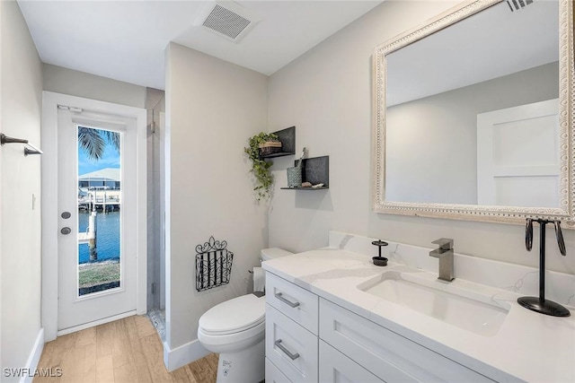 bathroom with hardwood / wood-style flooring, a water view, vanity, and toilet