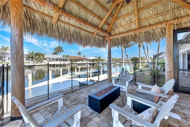 view of dock with a gazebo, a water view, a patio, and a fire pit