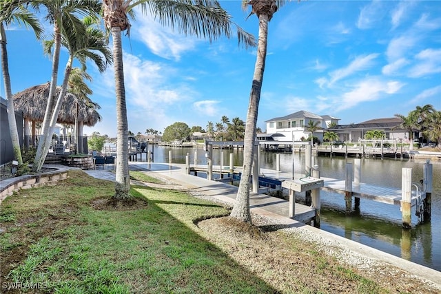 view of dock with a lawn and a water view