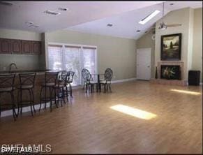 kitchen with hardwood / wood-style floors, lofted ceiling with skylight, sink, and a breakfast bar area