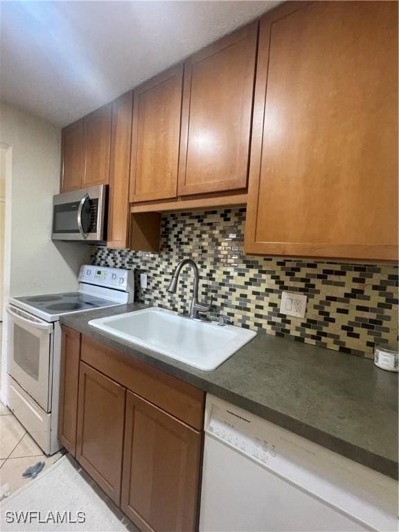 kitchen featuring sink, white appliances, light tile patterned floors, and backsplash