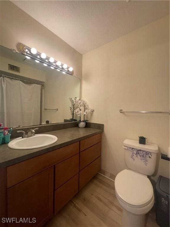 bathroom featuring vanity, hardwood / wood-style flooring, curtained shower, and toilet