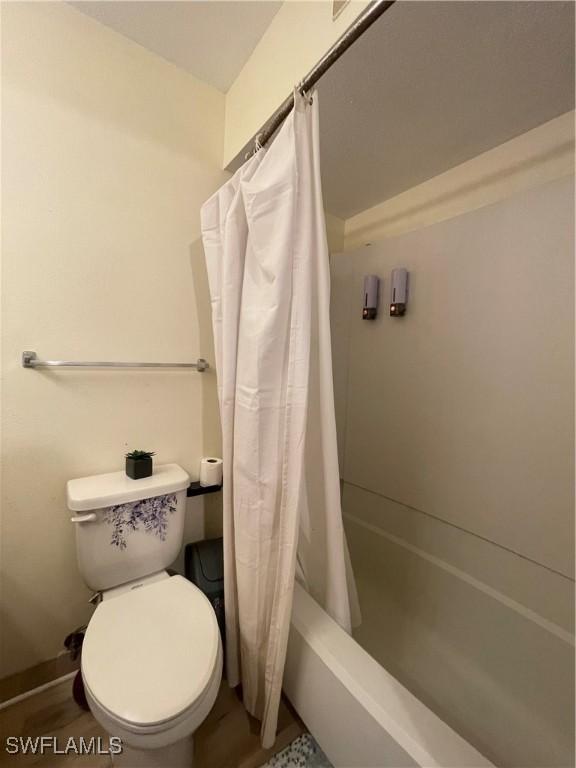 bathroom with shower / bath combination with curtain and toilet