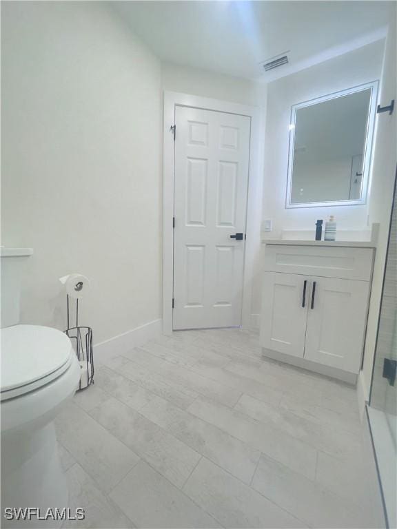 bathroom featuring vanity, a shower with shower door, and toilet